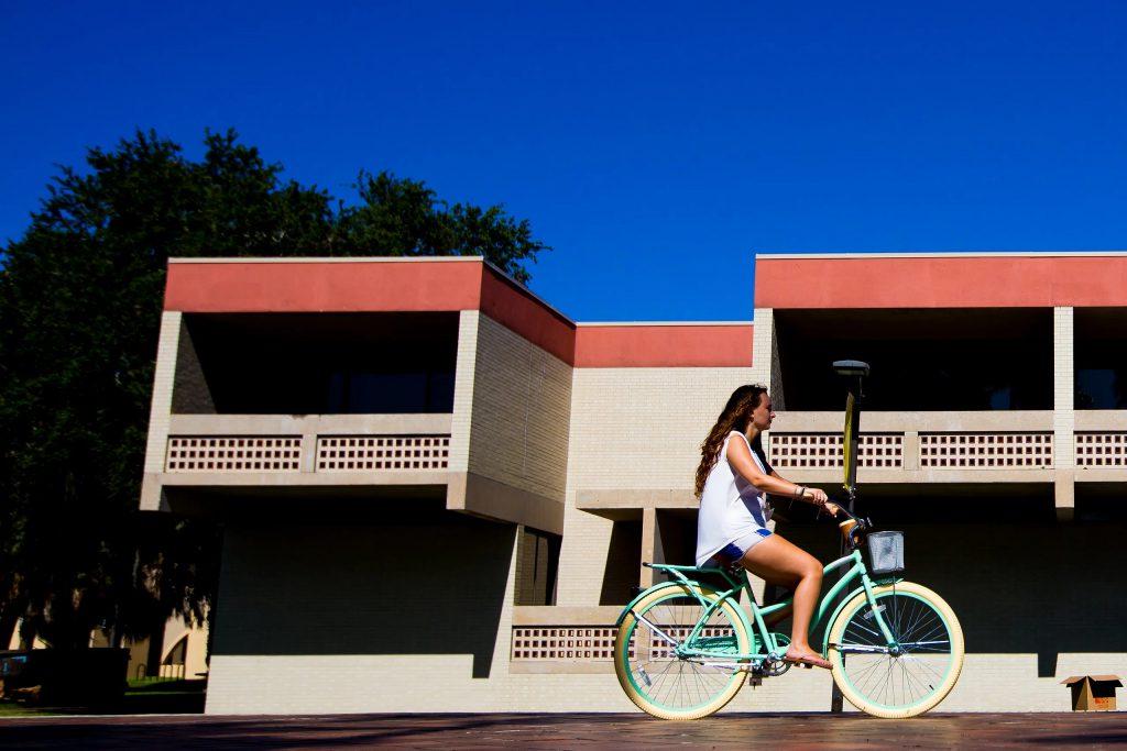 girl riding bike in front of NCF dormitory.